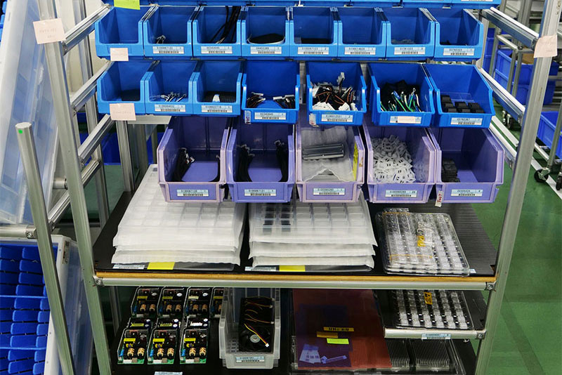 The parts used for assembling that day's run of V-600UHD units are set out in order. A label is affixed, indicating “Set-out complete.